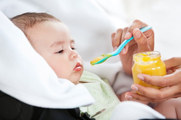 Close-up of a mother giving food to her adorable baby at home