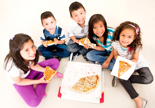 Happy group of kids eating pizza and smiling