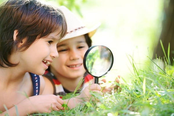 Happy kid exploring nature with magnifying glass-1