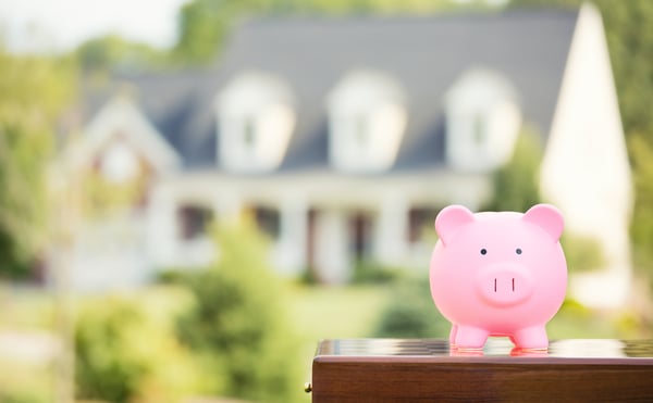 Real estate sale, home savings, loans market concept. Housing industry mortgage plan and residential tax saving strategy. Piggy bank isolated outside home on background. Focus on piggybank. Homeowner-1