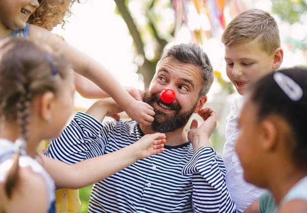 man with red nose playing with children