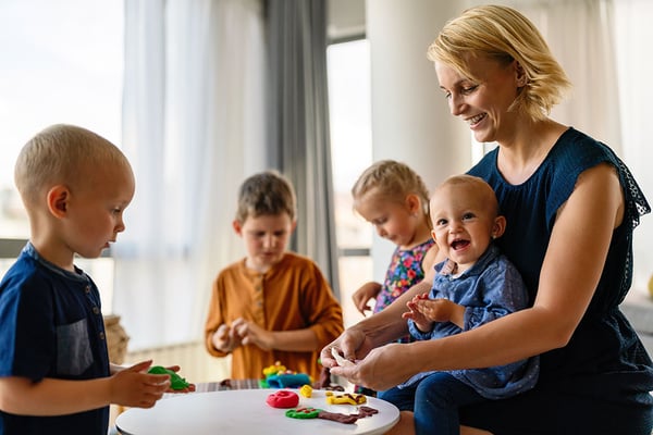 Woman playing with plasticine with children